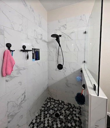 Marble-look shower tile with black fixtures and niche