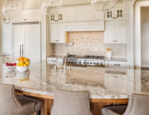 Luxury kitchen with cream cabinetry, granite counters, and custom range wall