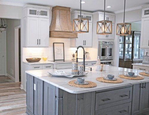 Kitchen remodel with gray island, white cabinets, pendant lighting, and wood-look floors