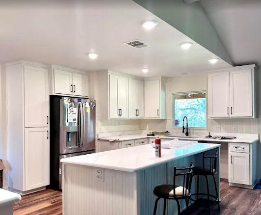 White kitchen remodel with large island and updated lighting