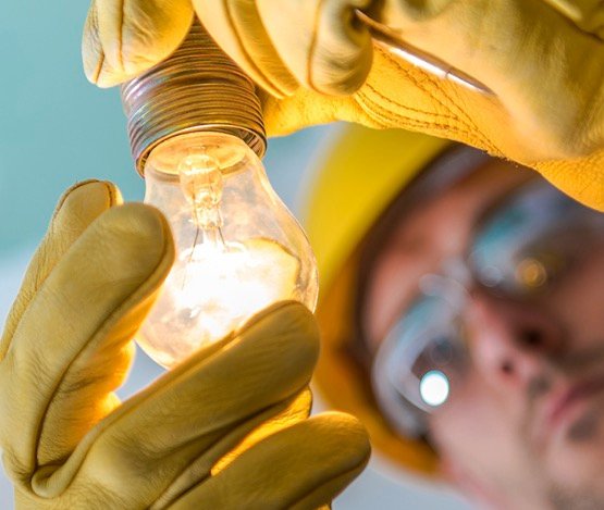 Electrician replacing a light bulb during electrical service