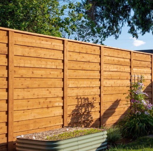 Warm horizontal wood privacy fence beside a garden
